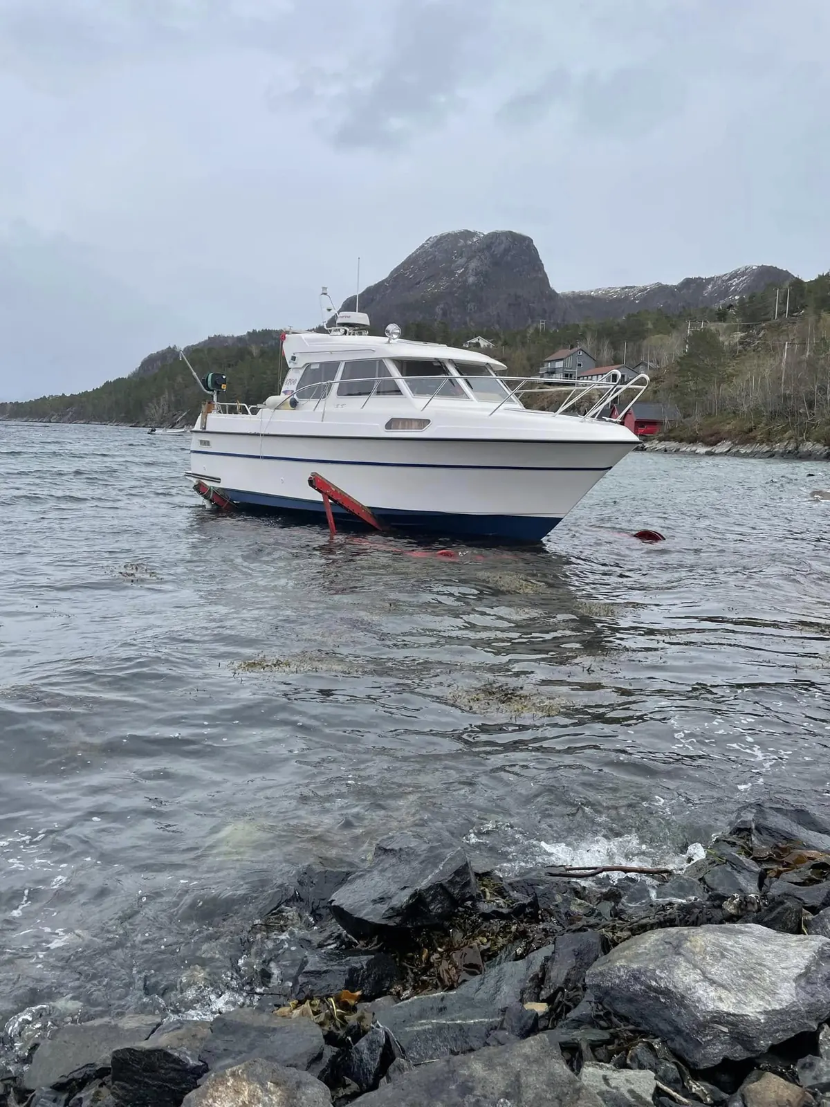 Hvit og blå kabinkrysser i vannkanten ved de røde armene på opplagsvogna