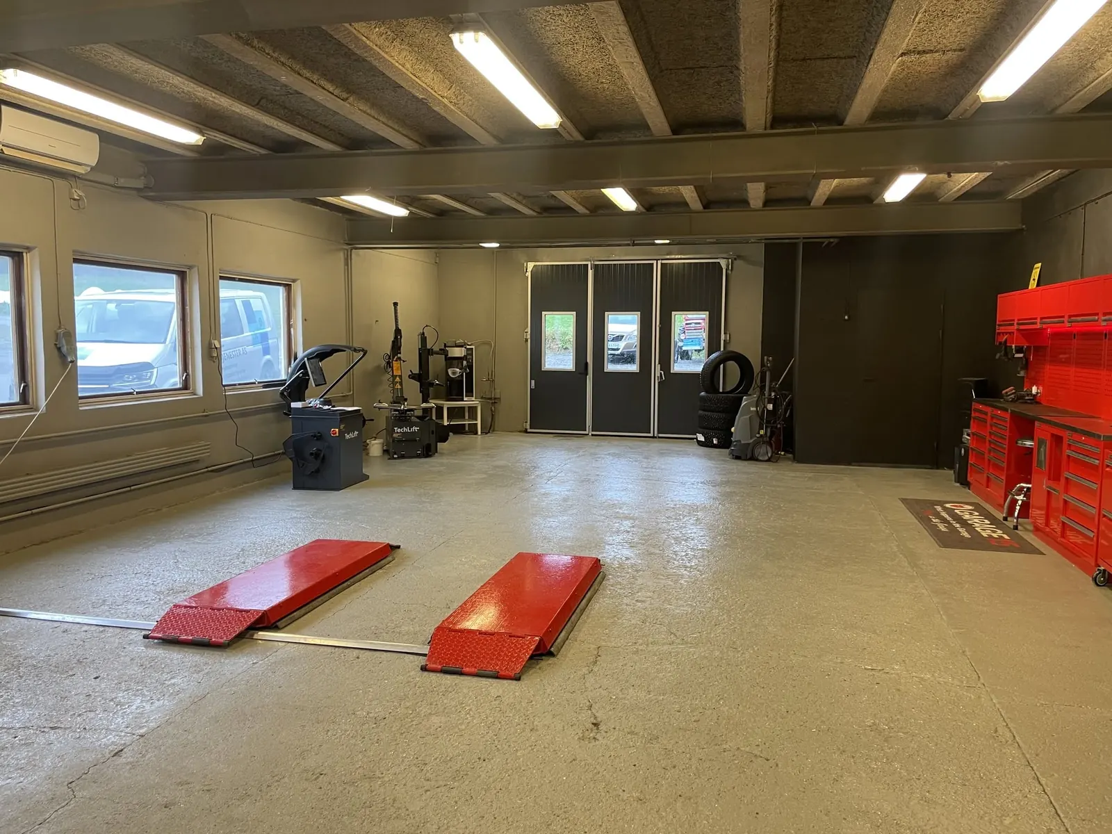 Verkstedhallen med dekkmaskin, avbalanseringsmaskin, kjøreramper og røde verktøyskap